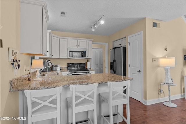 kitchen featuring light stone counters, stainless steel fridge, a peninsula, and electric stove