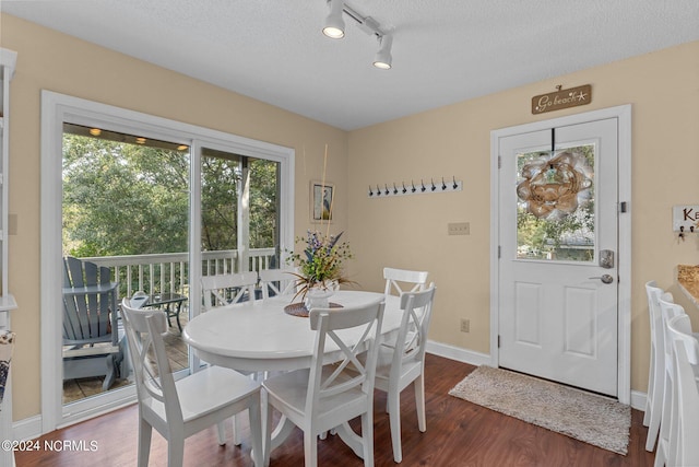 dining space with baseboards, a textured ceiling, and dark wood finished floors