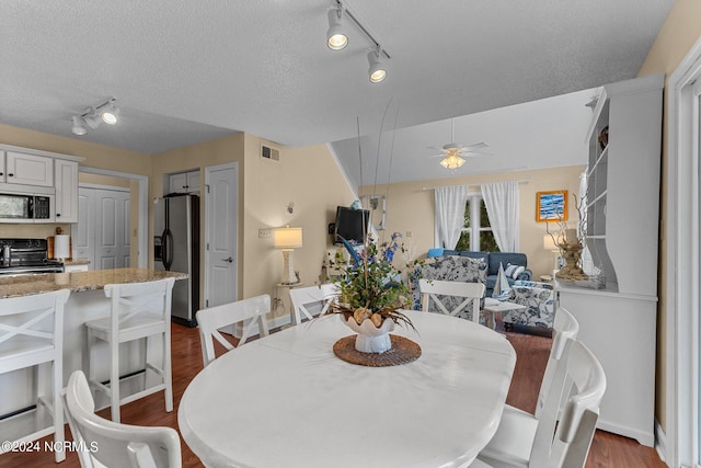 dining area with a ceiling fan, dark wood-style floors, visible vents, and a textured ceiling