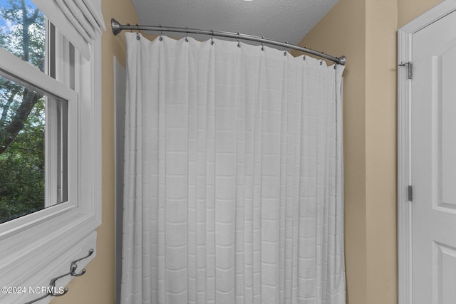 full bath featuring curtained shower and a textured ceiling