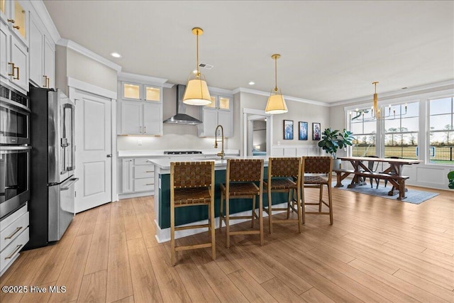 kitchen with visible vents, crown molding, light countertops, appliances with stainless steel finishes, and wall chimney exhaust hood