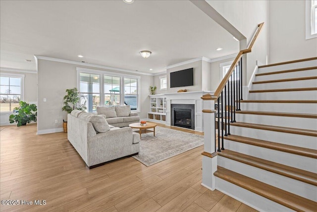 living area featuring baseboards, stairs, recessed lighting, light wood-style flooring, and a glass covered fireplace