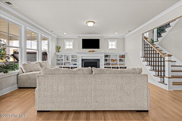 living area with visible vents, plenty of natural light, a fireplace, and light wood-type flooring