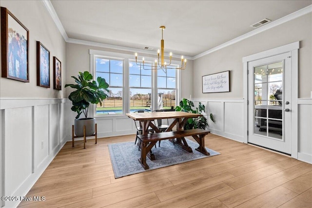 dining room with visible vents, light wood-type flooring, and ornamental molding