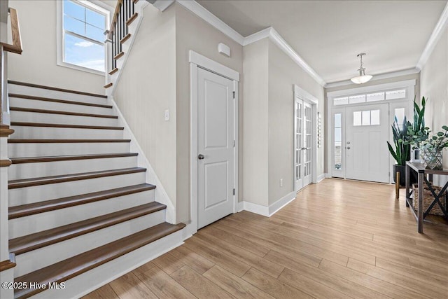 foyer featuring stairway, baseboards, crown molding, and light wood-style floors