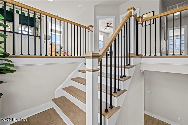 stairway featuring baseboards, wood finished floors, visible vents, and ceiling fan