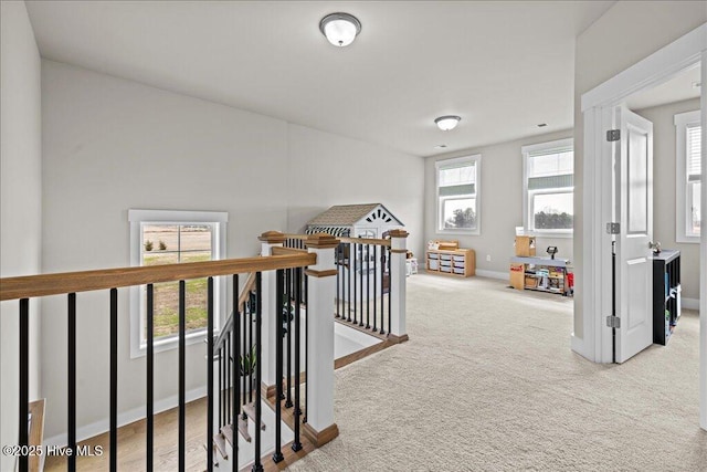 hall with carpet flooring, an upstairs landing, baseboards, and a healthy amount of sunlight