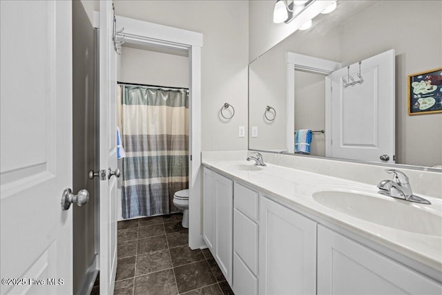 bathroom with a sink, toilet, a shower with shower curtain, and double vanity