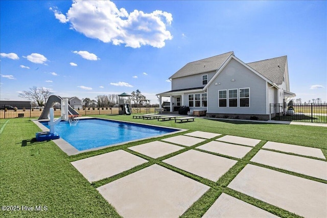 view of swimming pool featuring a patio, a lawn, a water slide, and fence