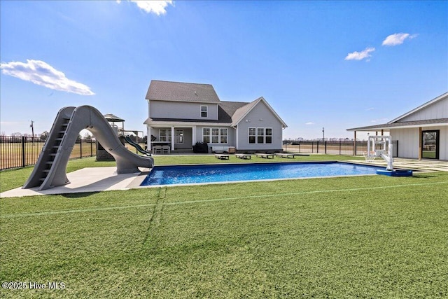 rear view of property with a fenced in pool, a patio, a lawn, and fence