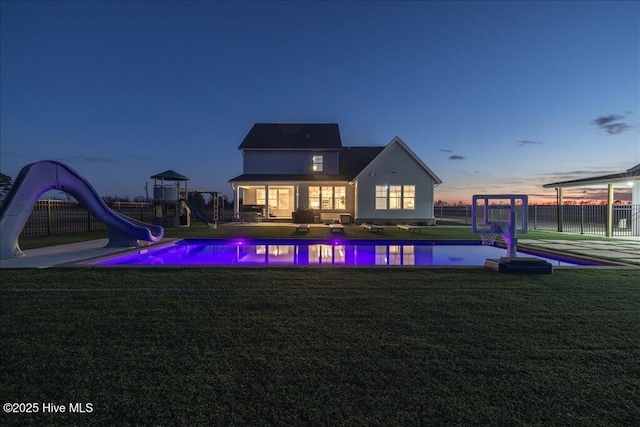 view of pool with a lawn, fence, playground community, a water slide, and a fenced in pool