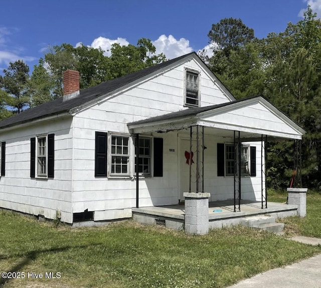 bungalow-style house featuring a chimney, a porch, and a front lawn