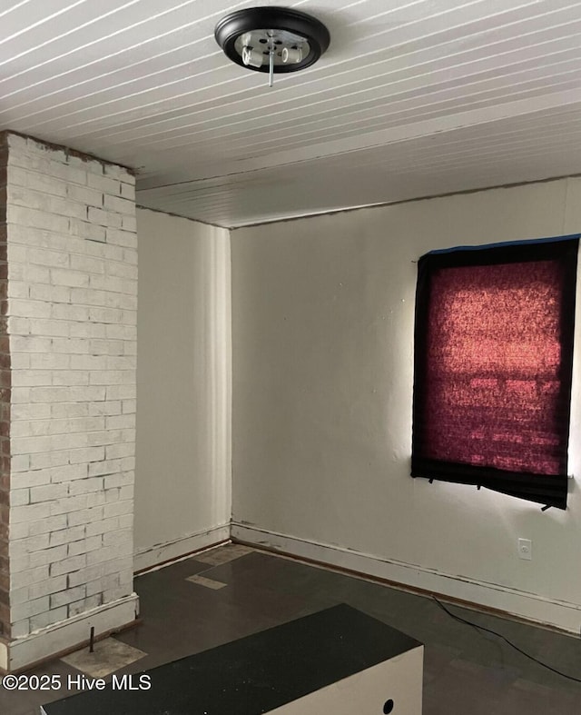 unfurnished room featuring brick wall and concrete flooring