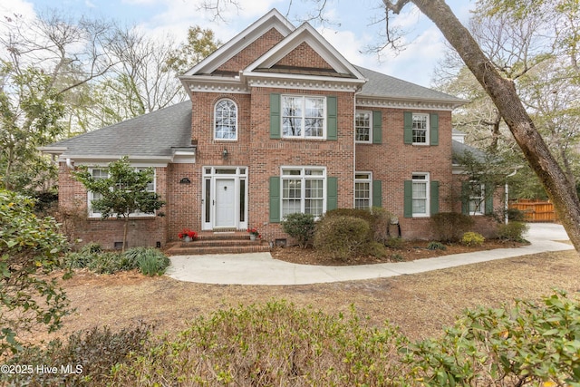 georgian-style home featuring brick siding, roof with shingles, and crawl space