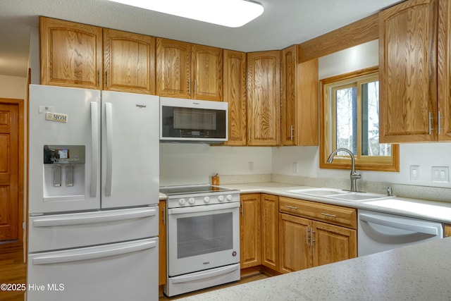 kitchen with brown cabinets, white appliances, light countertops, and a sink