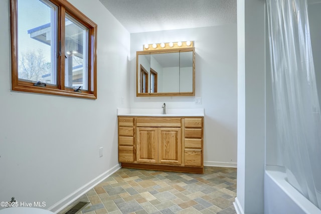 full bath featuring stone finish floor, baseboards, visible vents, and a textured ceiling