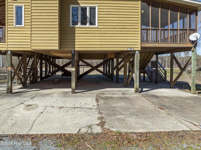 view of patio / terrace with stairway, a carport, driveway, and a sunroom