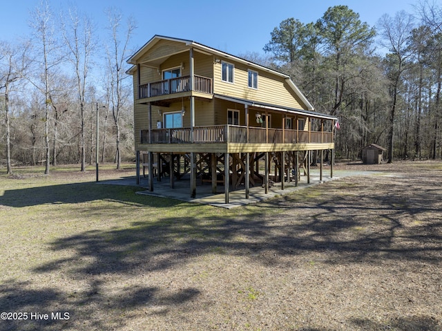 rear view of property featuring stairway, a storage shed, and an outdoor structure