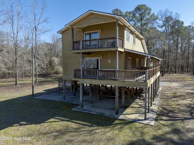 rear view of property featuring a carport, a lawn, and a wooden deck