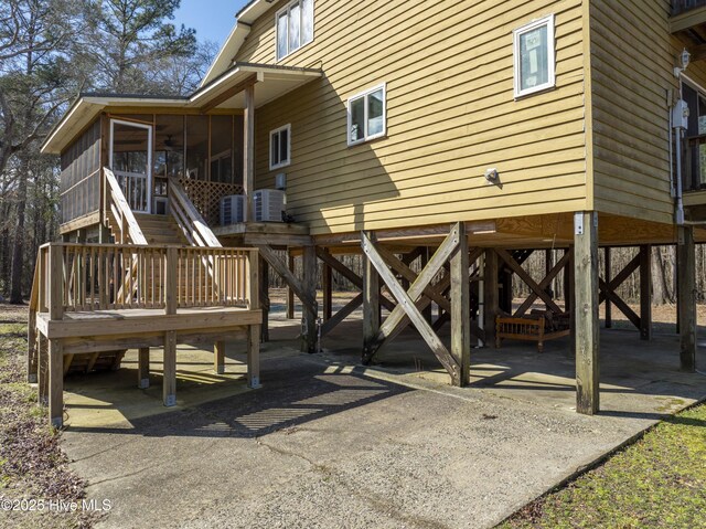 exterior space featuring a carport, stairway, central air condition unit, and a sunroom