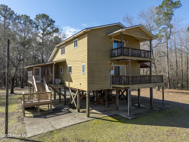 back of property featuring central air condition unit, a yard, a sunroom, a balcony, and stairs