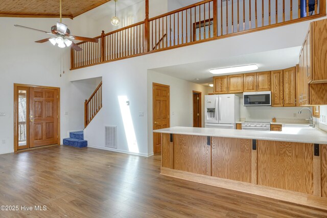 kitchen with wood finished floors, visible vents, electric range oven, a sink, and white fridge with ice dispenser