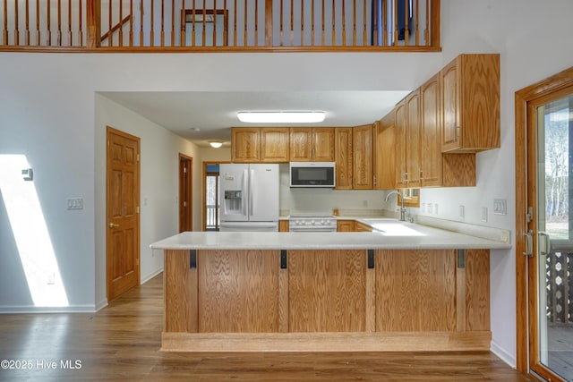 kitchen with white appliances, light countertops, a peninsula, and a sink