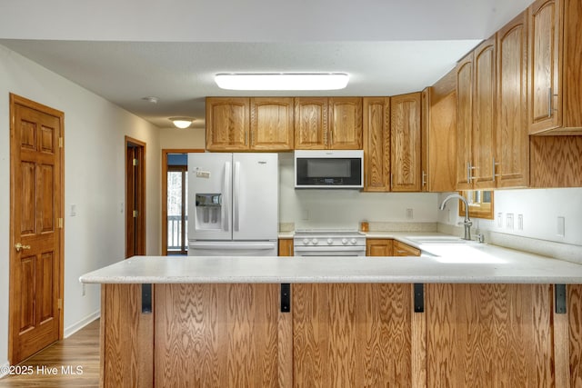 kitchen with light countertops, electric range oven, white fridge with ice dispenser, and a sink