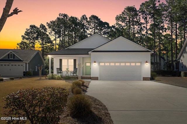 single story home featuring a porch, concrete driveway, and an attached garage