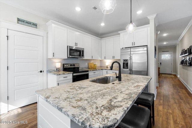 kitchen featuring dark wood-style floors, a sink, decorative backsplash, appliances with stainless steel finishes, and crown molding