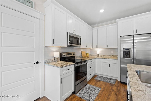 kitchen featuring white cabinetry, dark wood-type flooring, tasteful backsplash, and stainless steel appliances