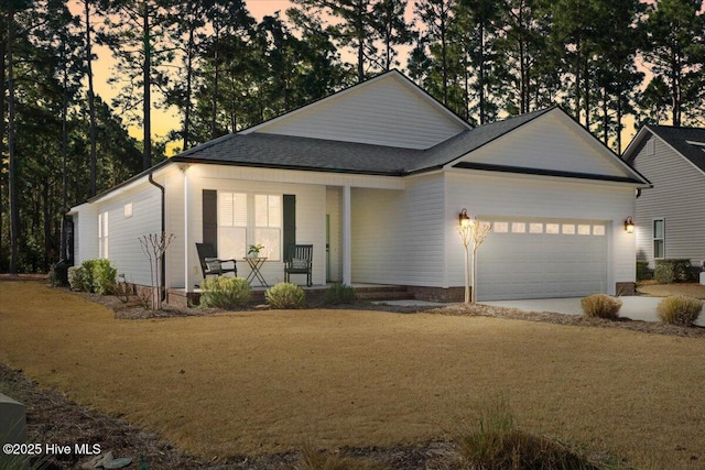 view of front facade with a front lawn, a porch, roof with shingles, driveway, and an attached garage