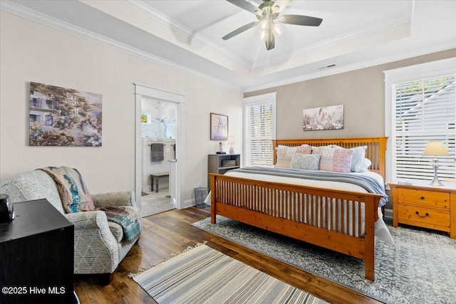 bedroom featuring visible vents, a tray ceiling, ornamental molding, wood finished floors, and a ceiling fan