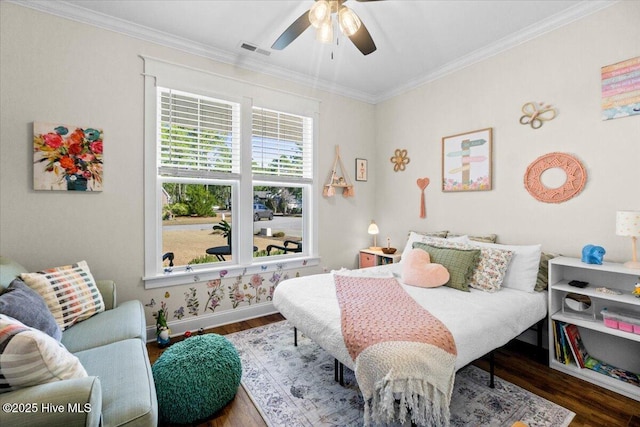 bedroom with visible vents, wood finished floors, baseboards, and ornamental molding