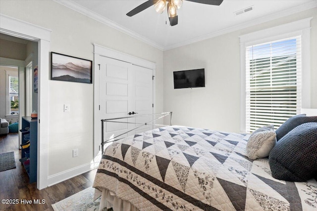 bedroom featuring wood finished floors, visible vents, baseboards, ceiling fan, and crown molding