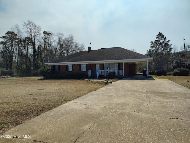 ranch-style house featuring driveway, a porch, a front yard, a carport, and a chimney