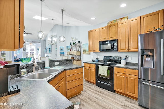 kitchen featuring dark countertops, vaulted ceiling, light wood-style flooring, black appliances, and a sink