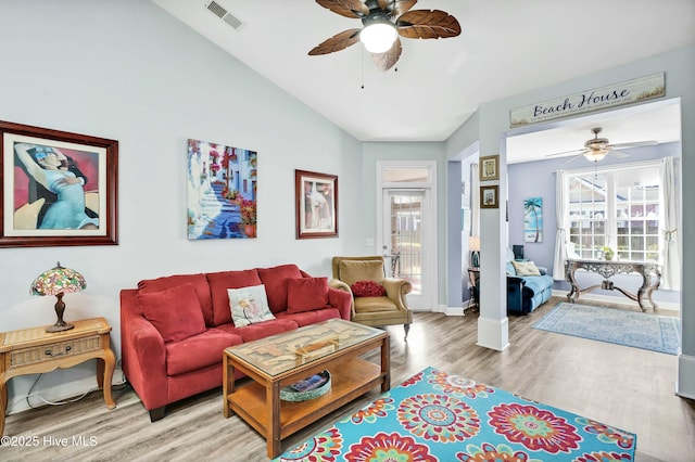 living room featuring vaulted ceiling, visible vents, plenty of natural light, and wood finished floors