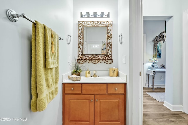 bathroom featuring baseboards, wood finished floors, and vanity