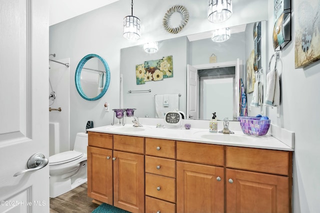 full bath with double vanity, toilet, wood finished floors, and a sink