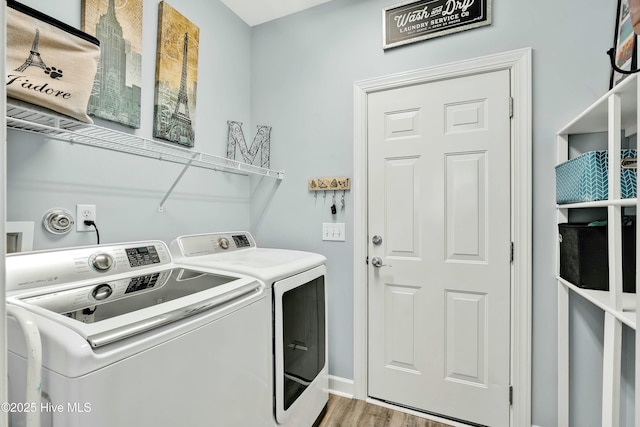 washroom with washing machine and clothes dryer, laundry area, and light wood-type flooring