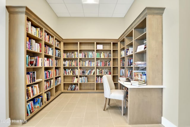 office with bookshelves, a drop ceiling, and light tile patterned floors