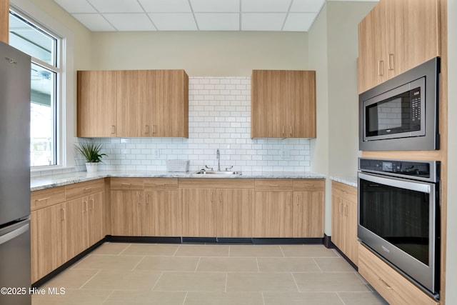 kitchen featuring a sink, stainless steel appliances, and light brown cabinetry