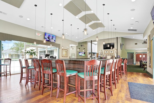 interior space featuring visible vents, pendant lighting, wood finished floors, and a community bar