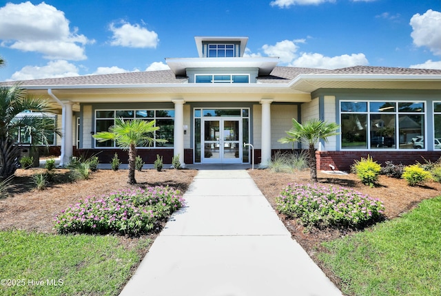 entrance to property with french doors, brick siding, and a shingled roof