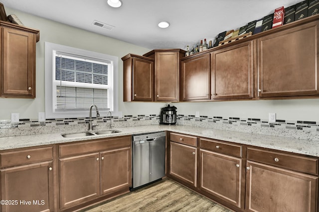 kitchen with visible vents, a sink, light wood finished floors, light stone countertops, and dishwasher