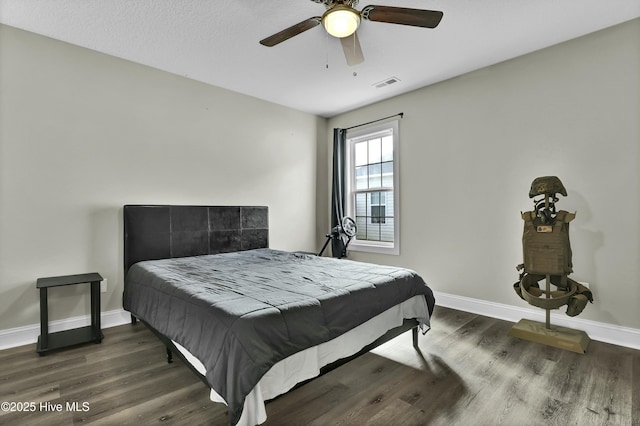 bedroom with a ceiling fan, wood finished floors, visible vents, and baseboards