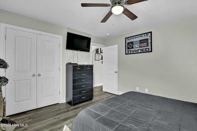 bedroom featuring baseboards, wood finished floors, a closet, and ceiling fan