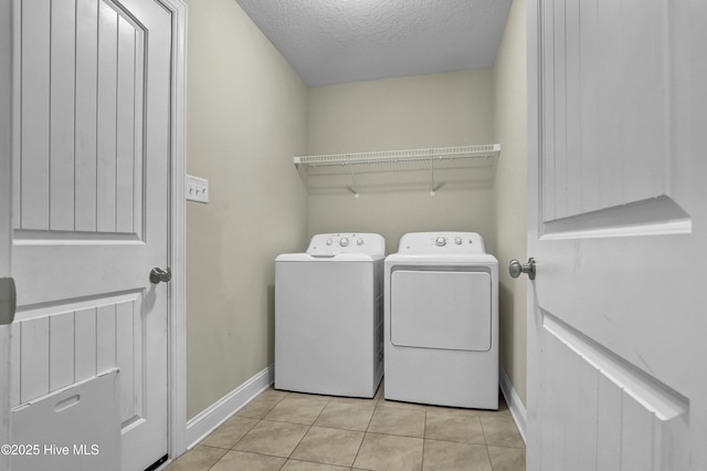 washroom with baseboards, washer and clothes dryer, laundry area, tile patterned floors, and a textured ceiling