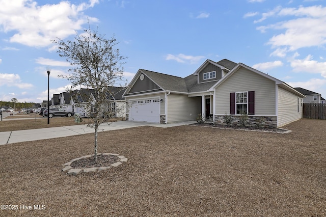 view of front facade with stone siding, fence, concrete driveway, an attached garage, and a shingled roof